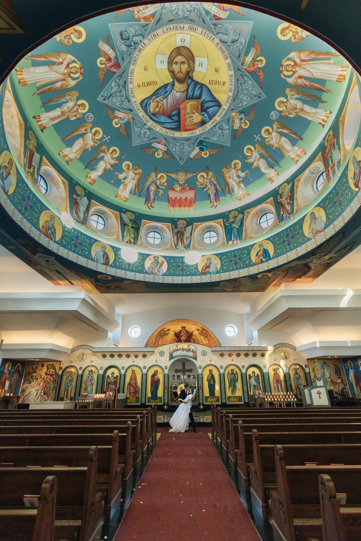 A couple stands beneath the dome of their Greek Orthodox church