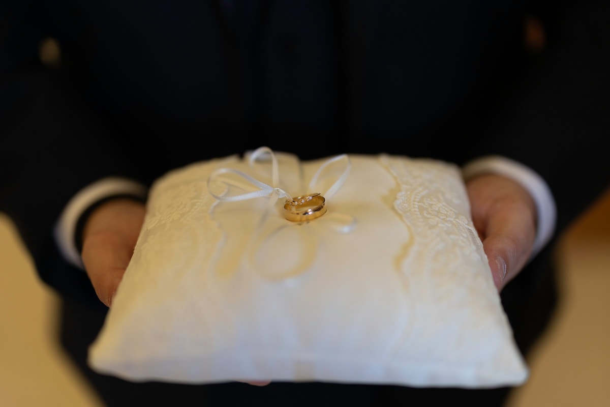 A wedding ring resting on a white ring pillow
