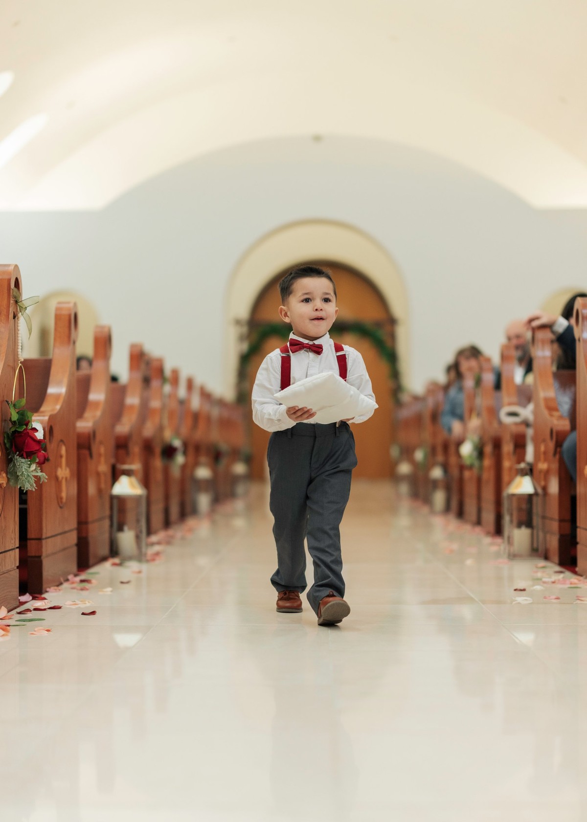 A young ring bearer walks down the church aisle