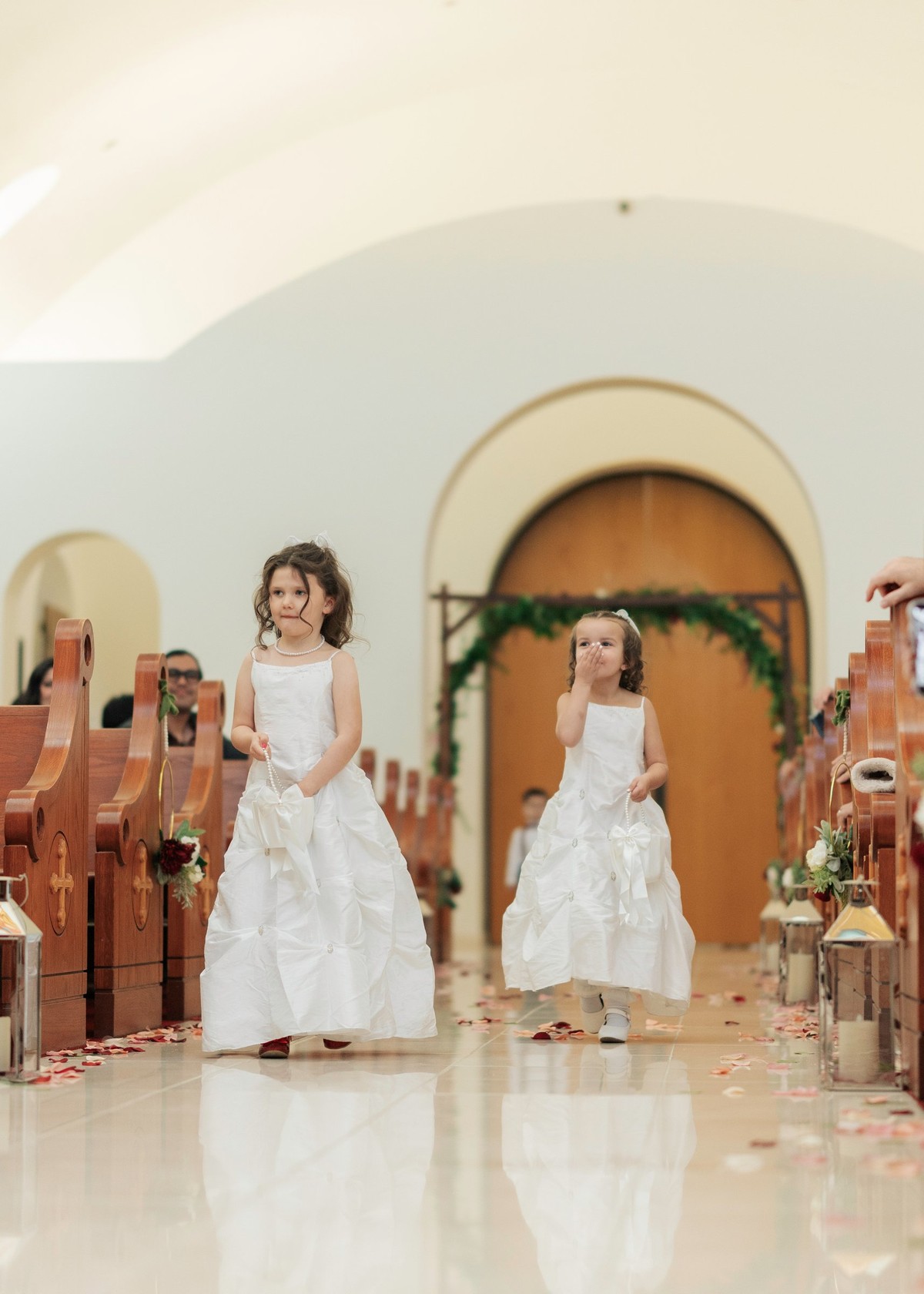 Two flower girls walk down the aisle together