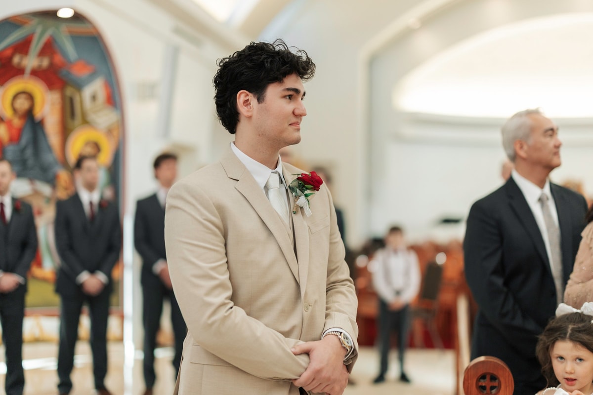 The groom watches the bride enter the church