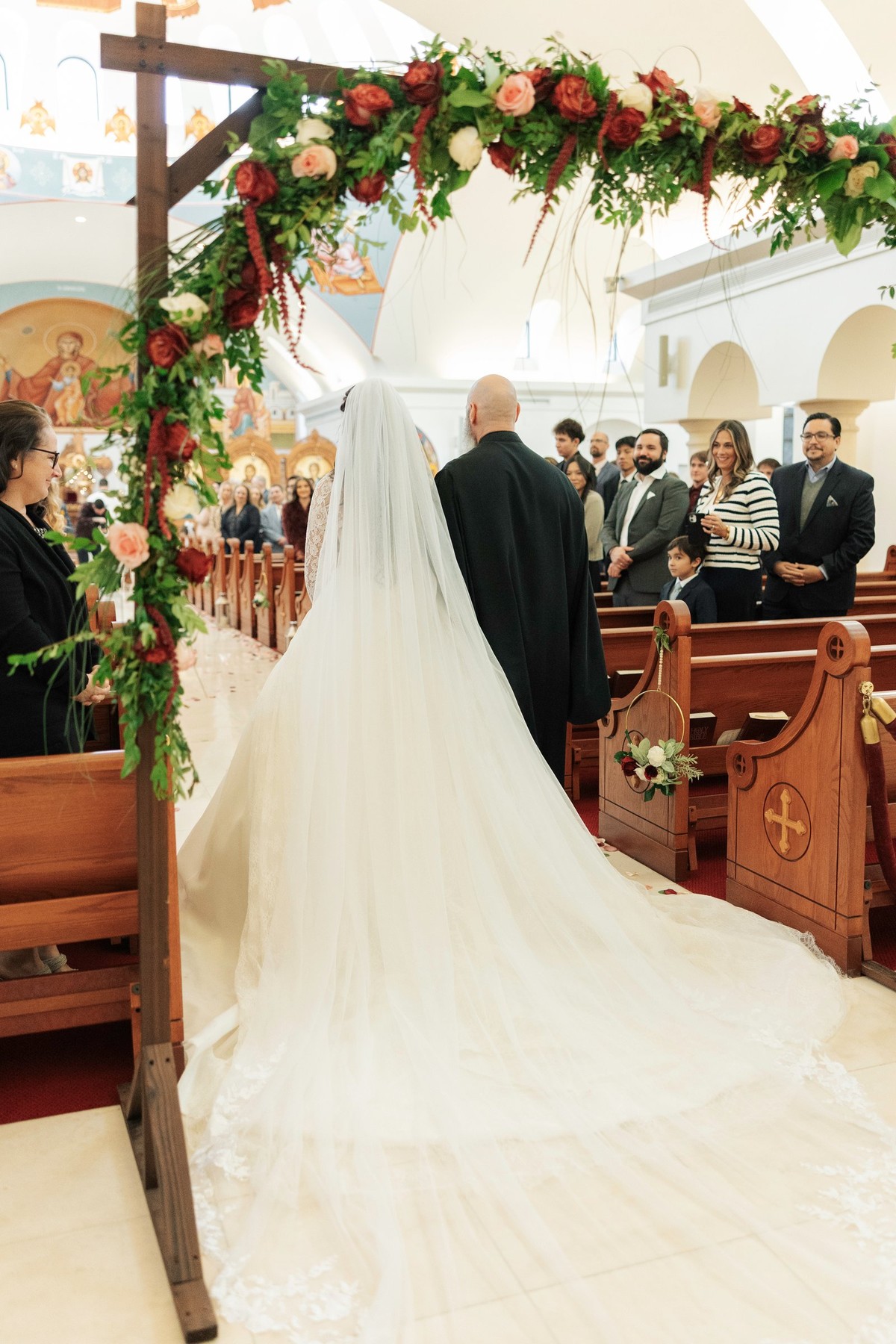 A bride approaches the front of the church with an older man