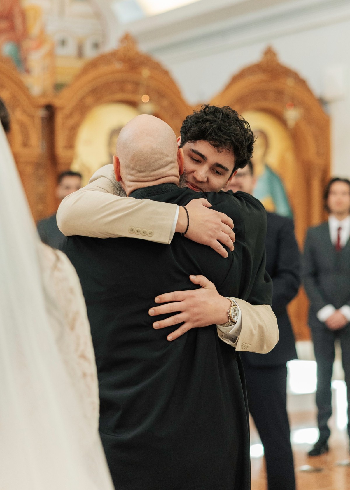 The groom embraces a man in a dark suit