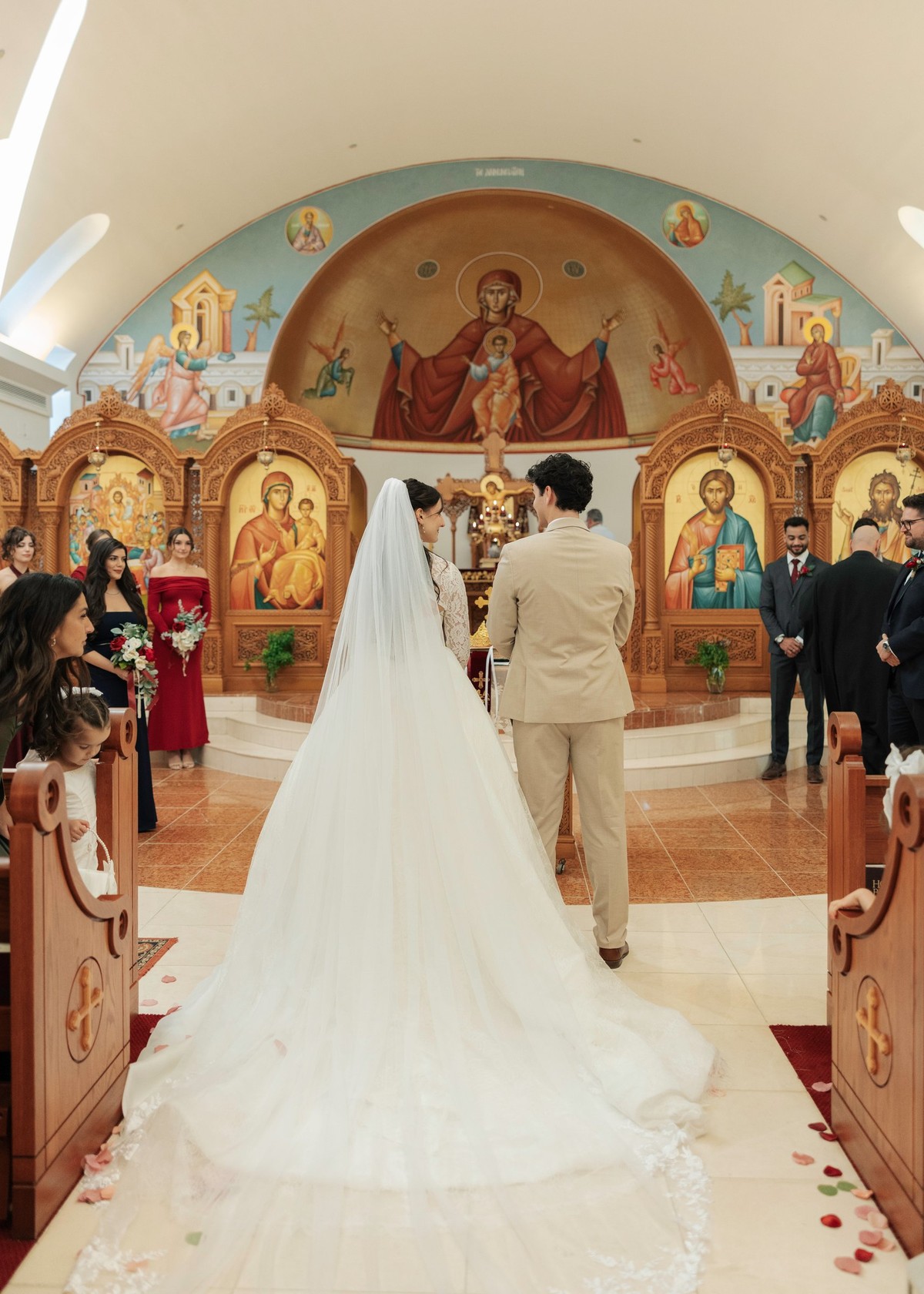 The bride and groom stand together before the iconostasis