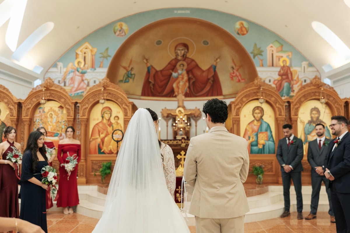 The bride and groom stand together before the iconostasis