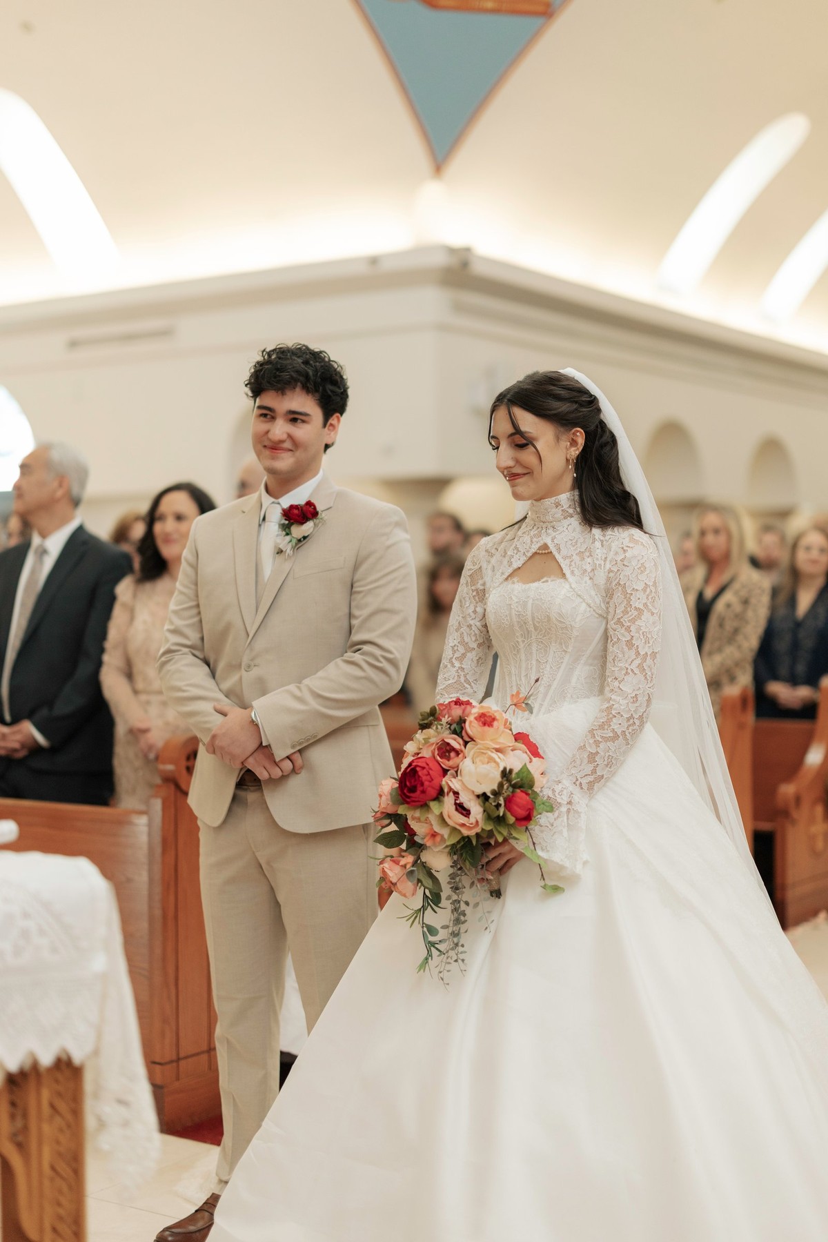 The bride and groom stand side by side at the front of the church