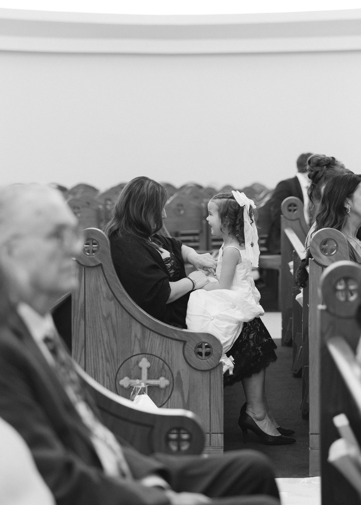 A child kneels on a pew during the ceremony in a black-and-white photograph