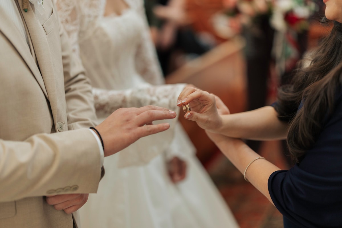 A wedding ring is placed on the groom's hand