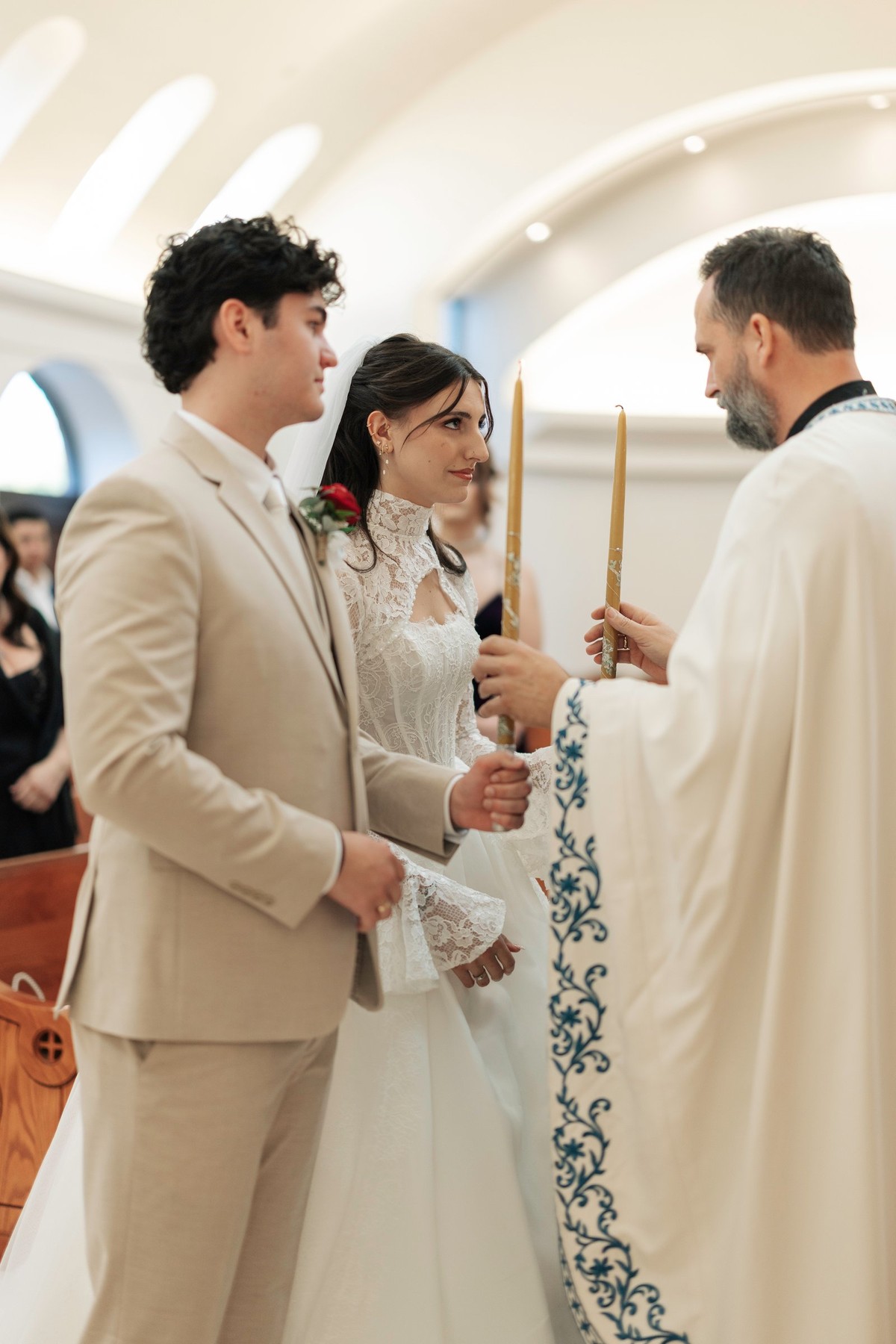 The bride and groom hold lighted candles before the priest