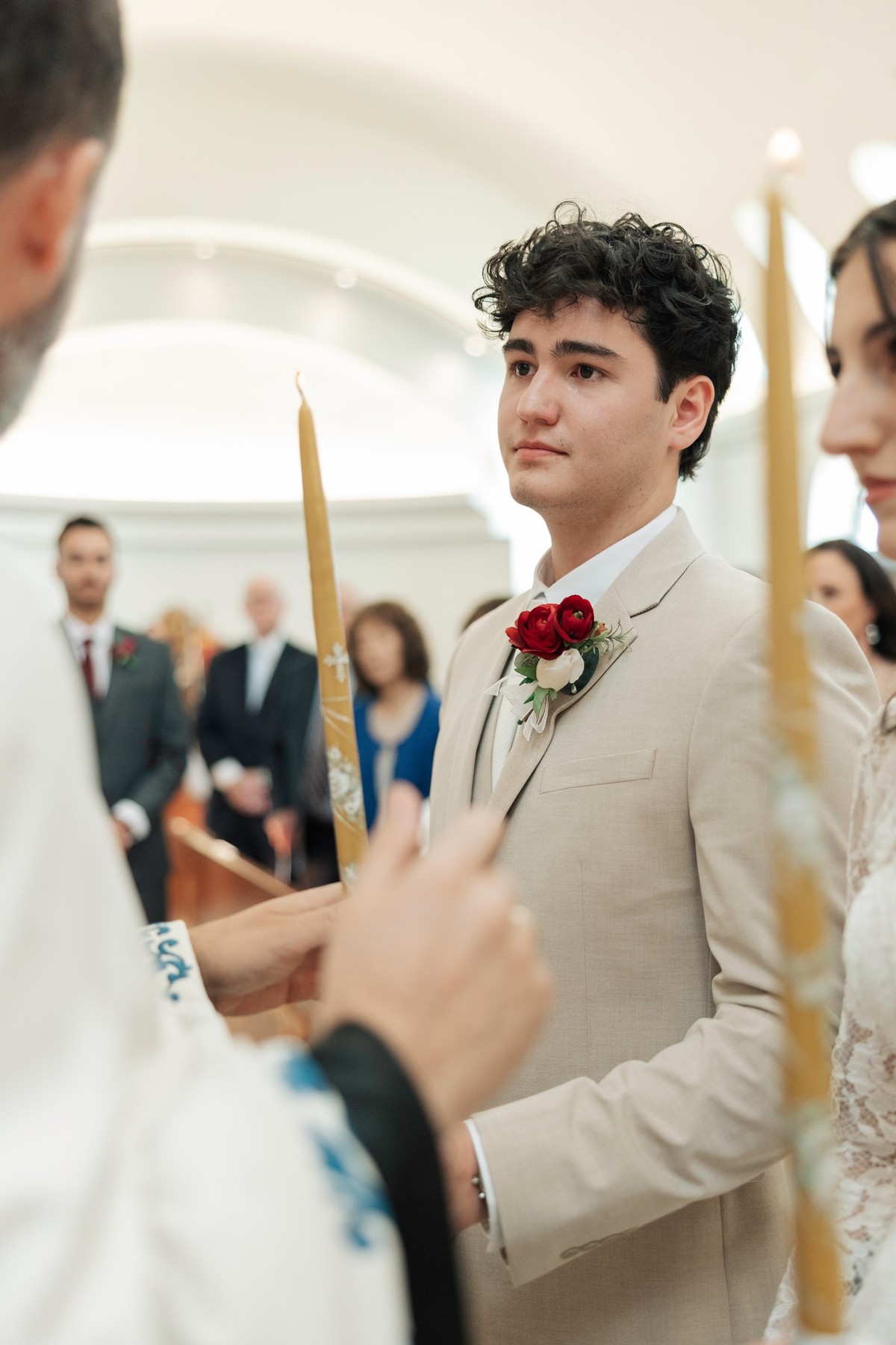 The bride and groom hold lighted candles before the priest