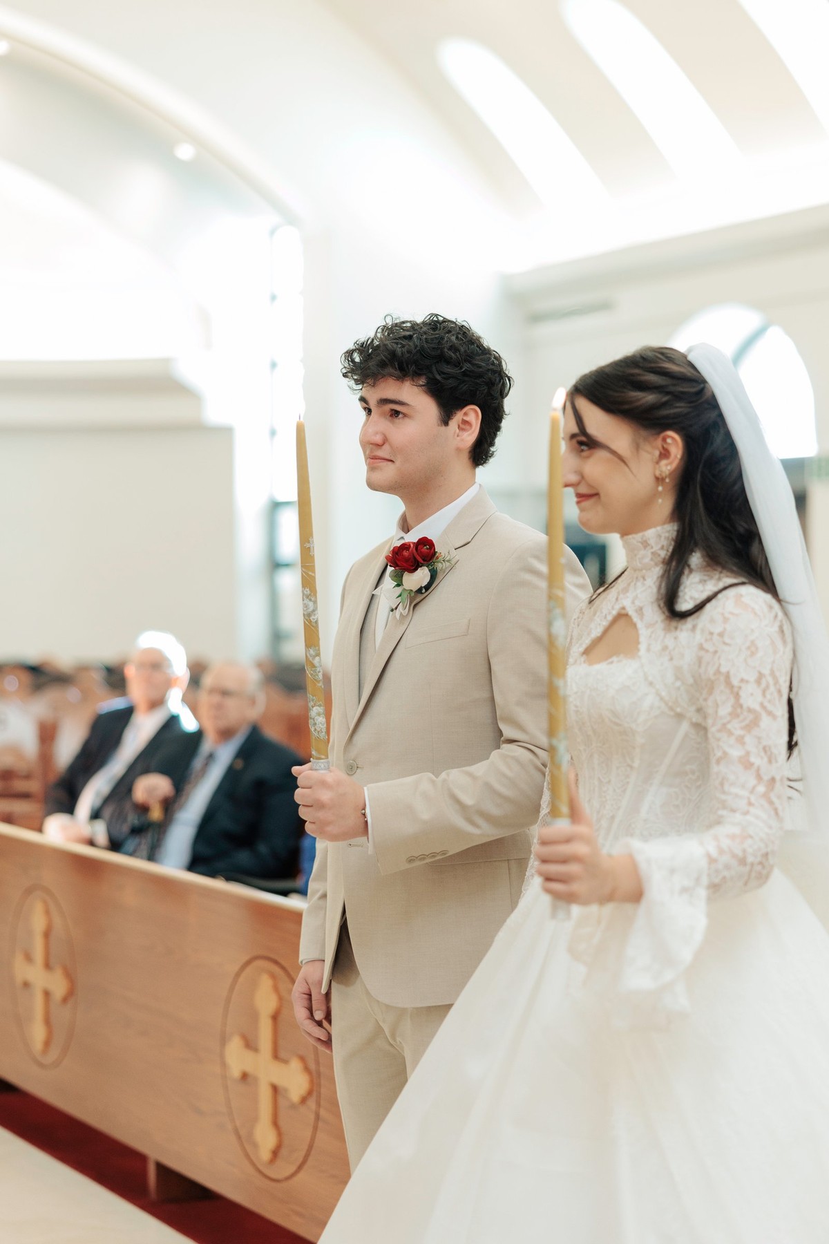 The bride and groom walk together holding wedding candles