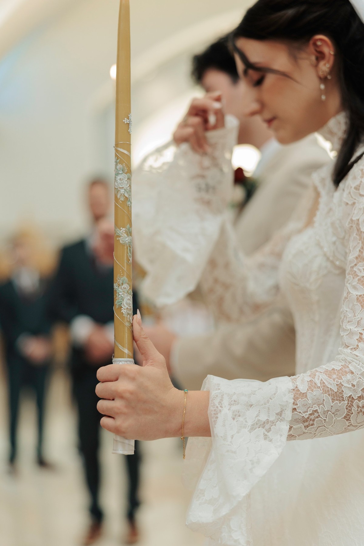 The bride holds a lighted wedding candle