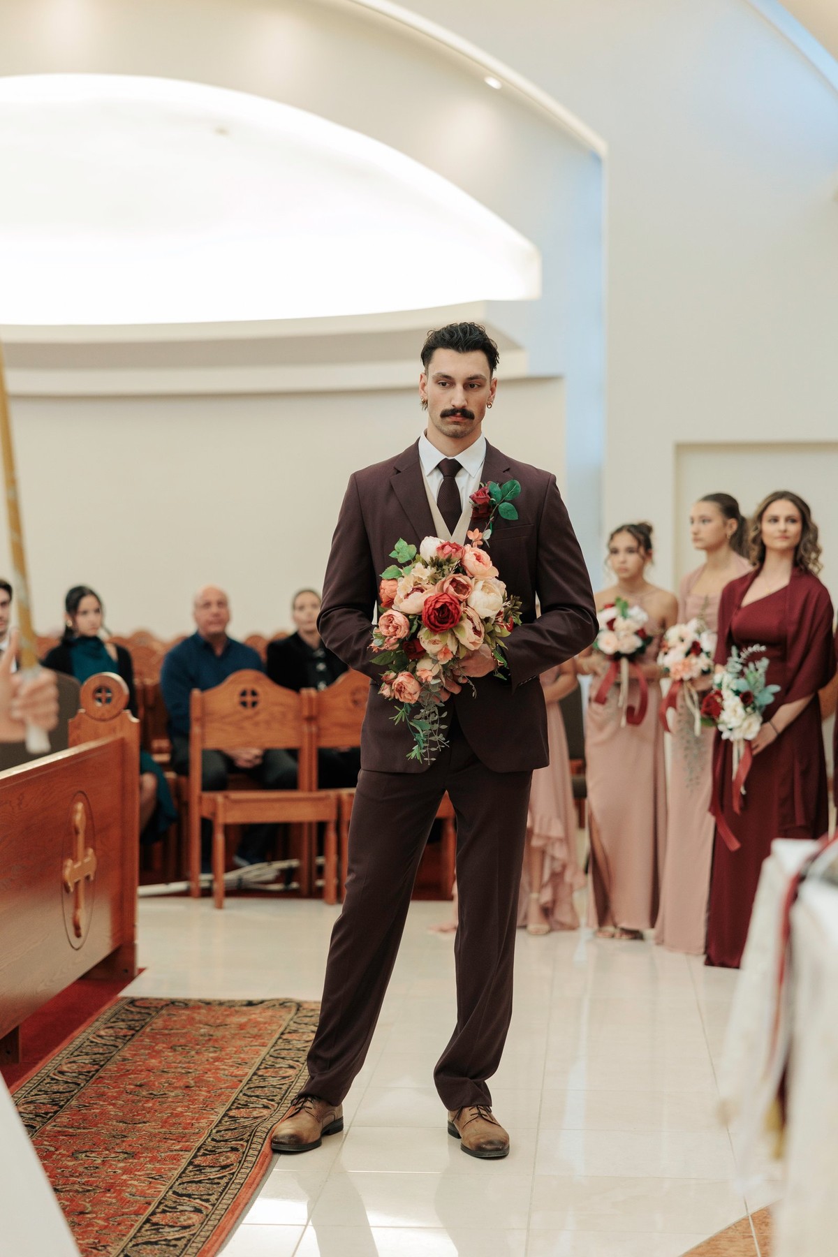 A man in a dark suit holds a lighted candle