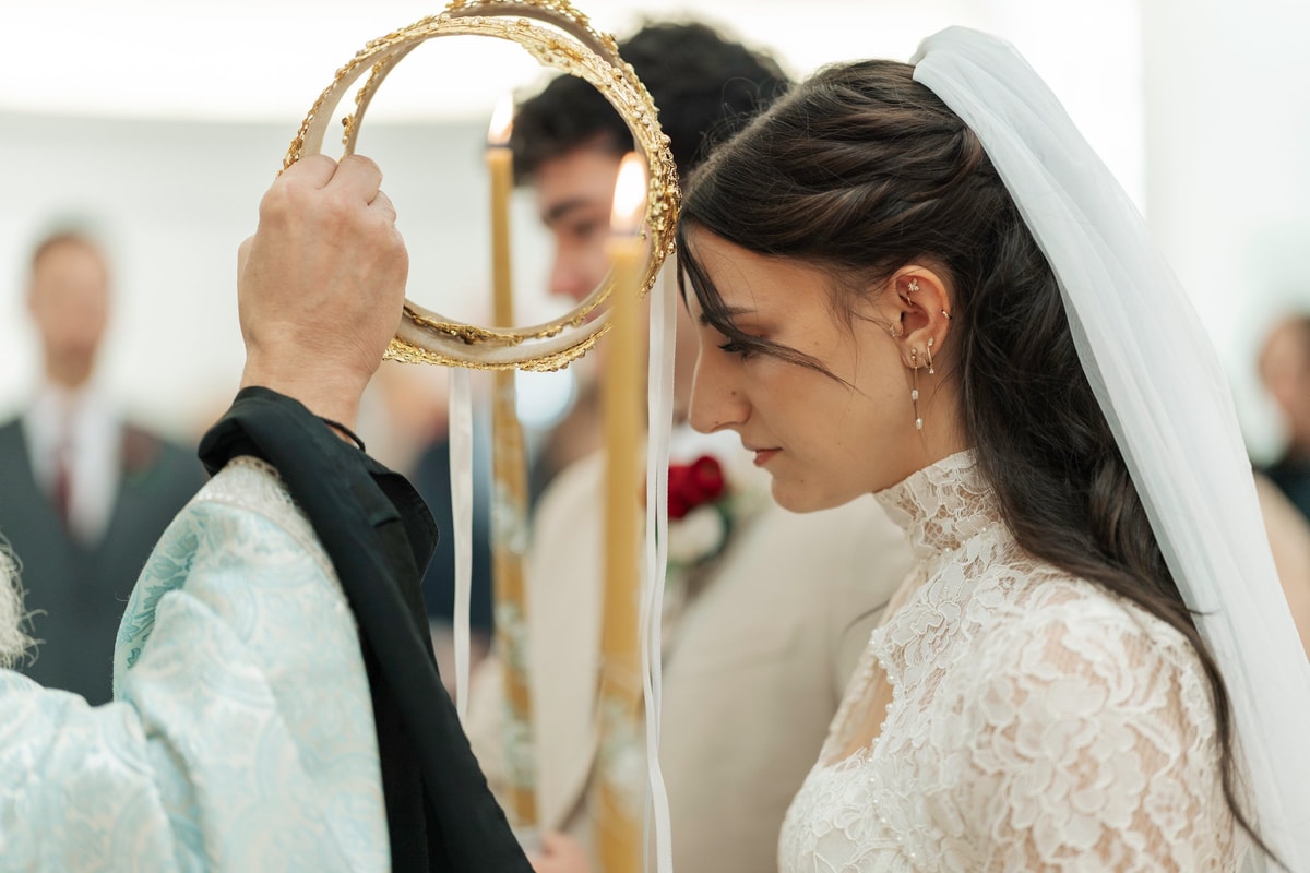 An Orthodox priest holds an ornate wedding crown above the bride