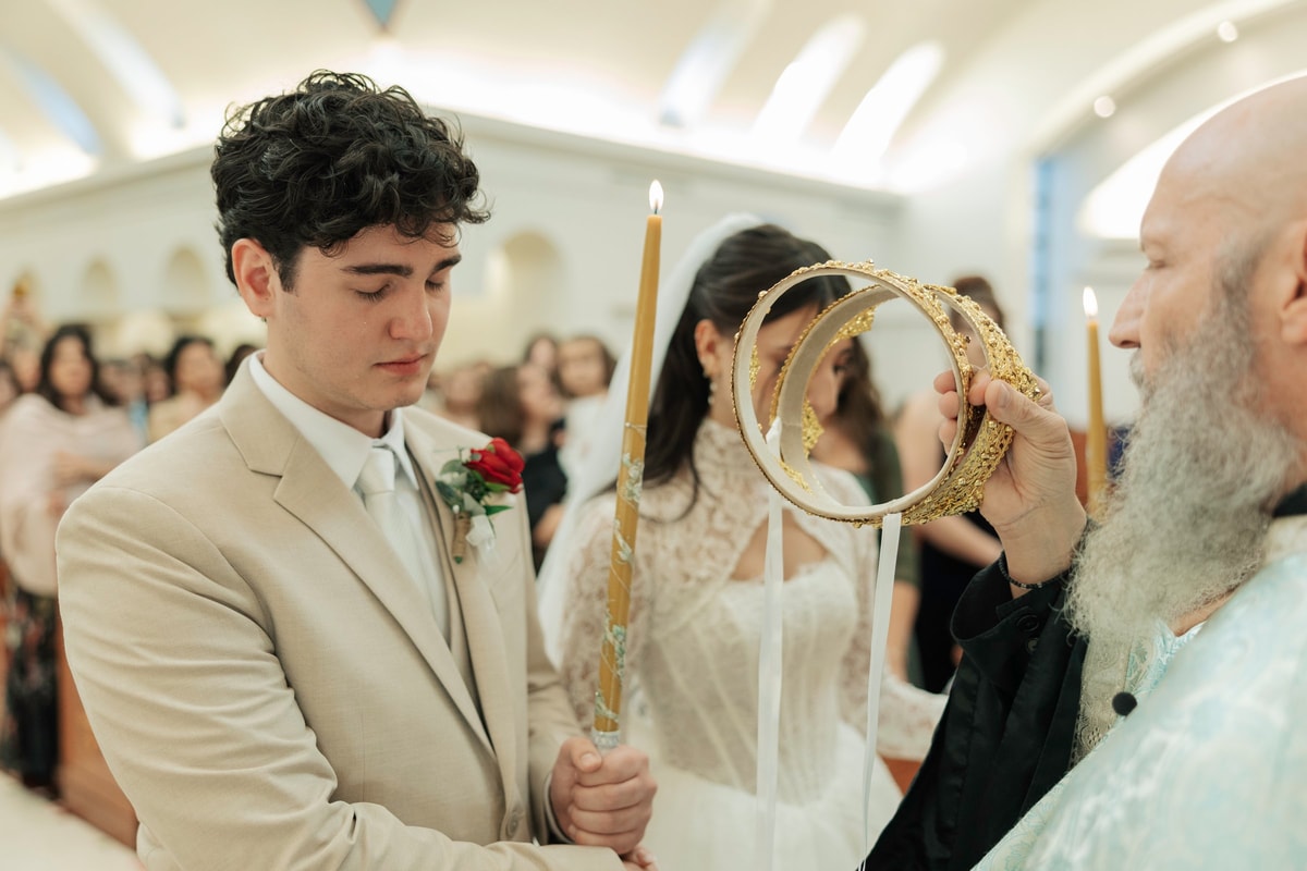 An Orthodox priest holds wedding crowns above the bride and groom