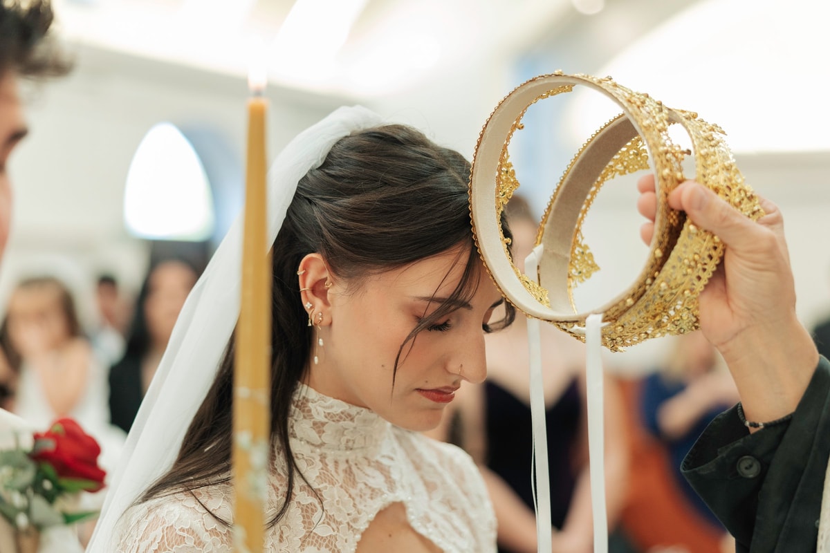 An Orthodox priest holds an ornate wedding crown above the bride