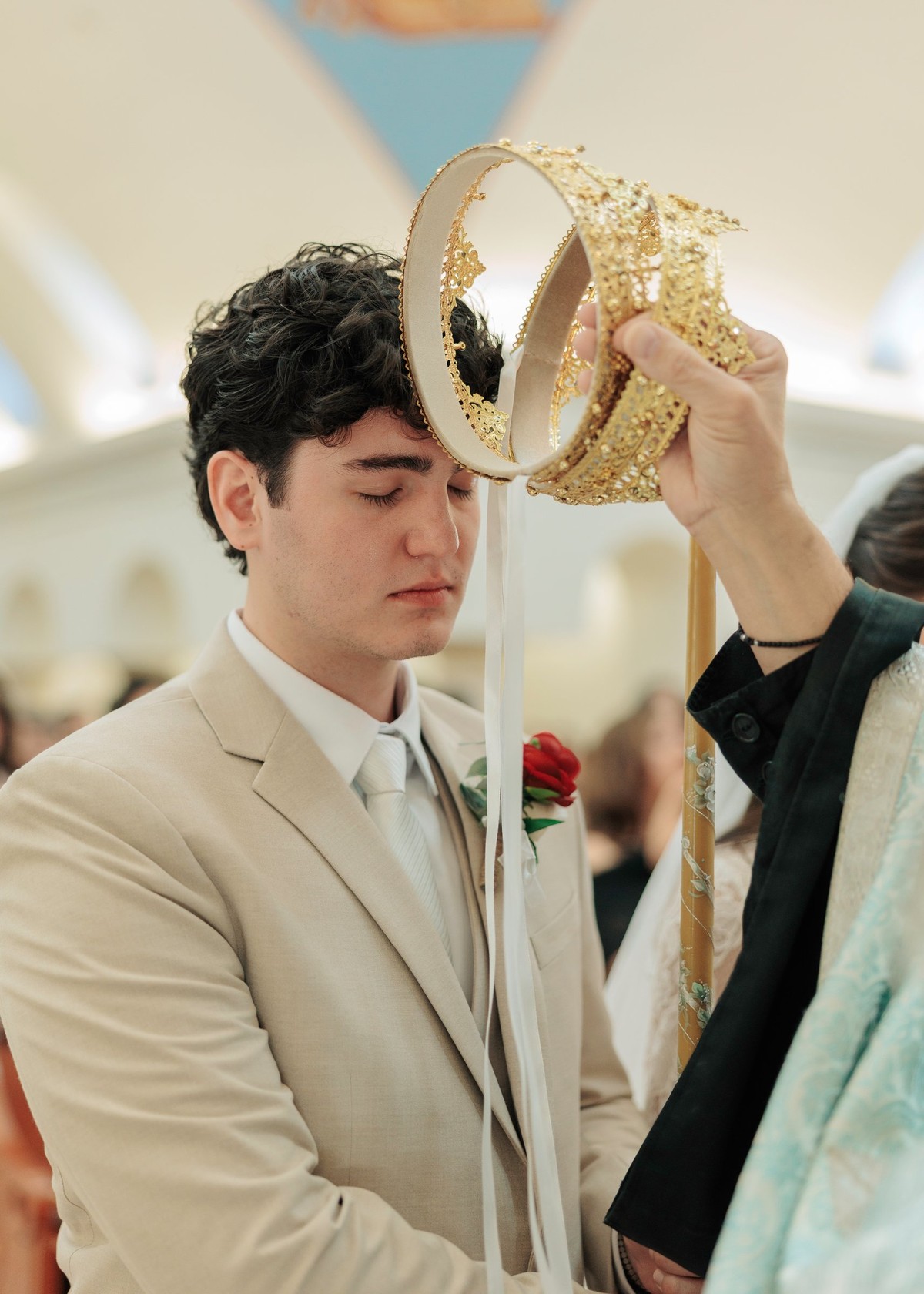 An Orthodox priest holds an ornate wedding crown above the groom