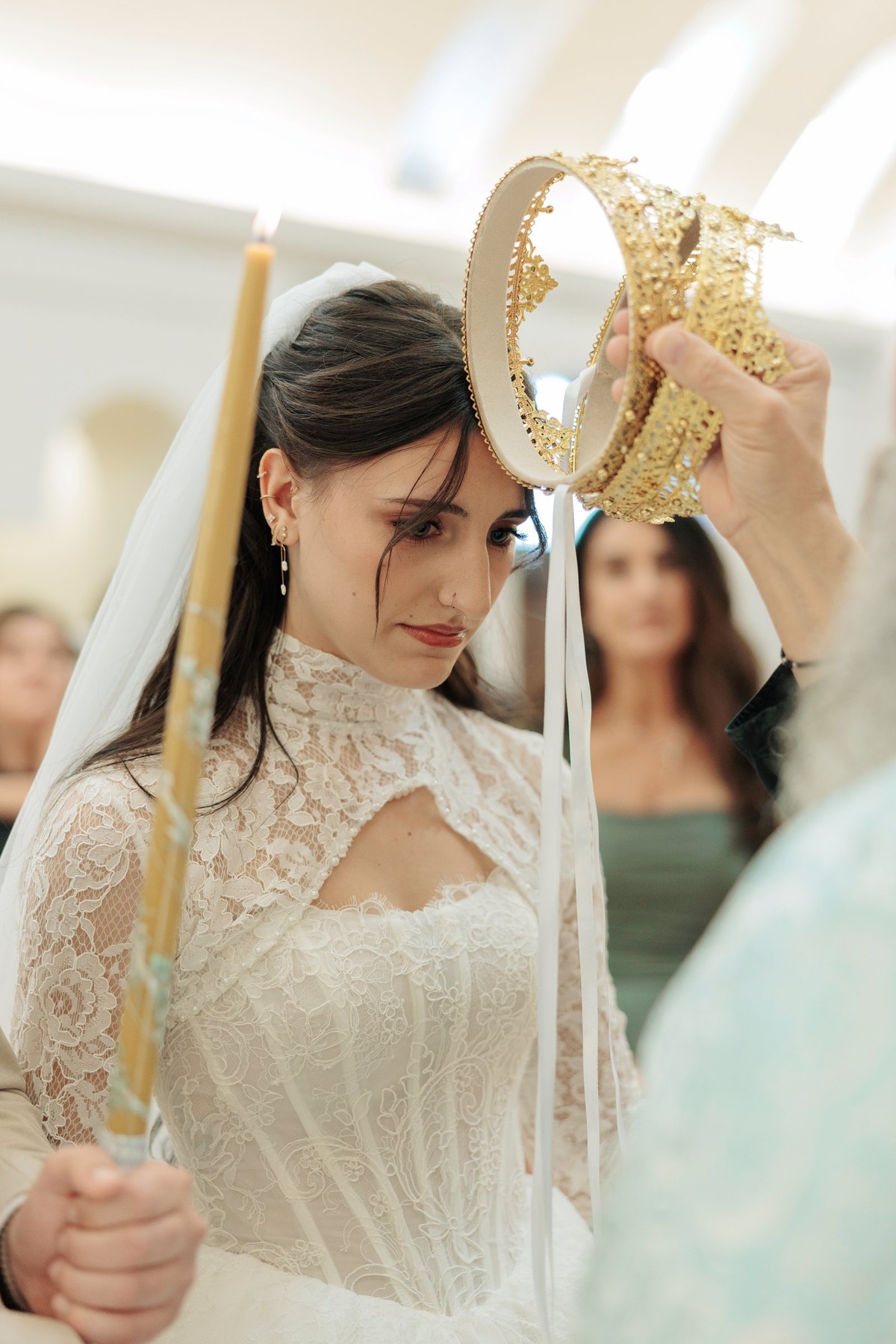 An Orthodox priest holds an ornate wedding crown above the bride