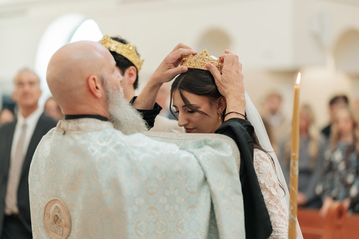 A priest places the wedding crown on the bride