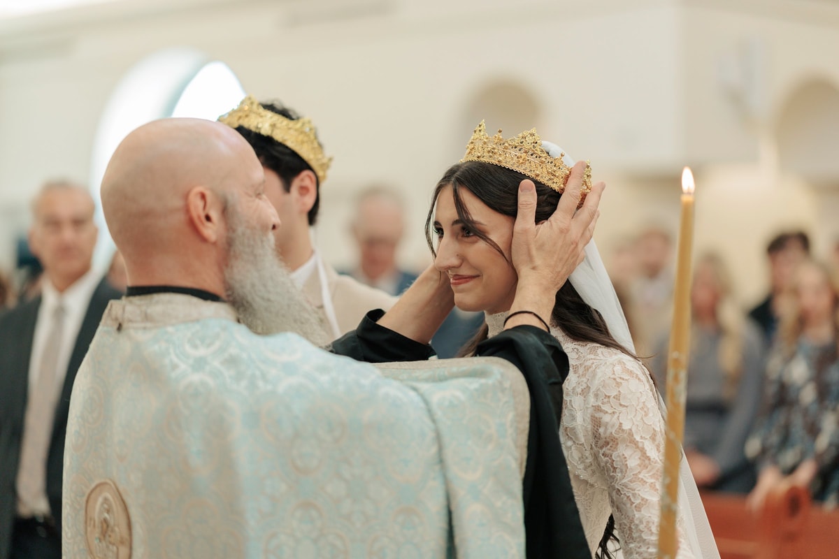 A priest places the wedding crown on the bride