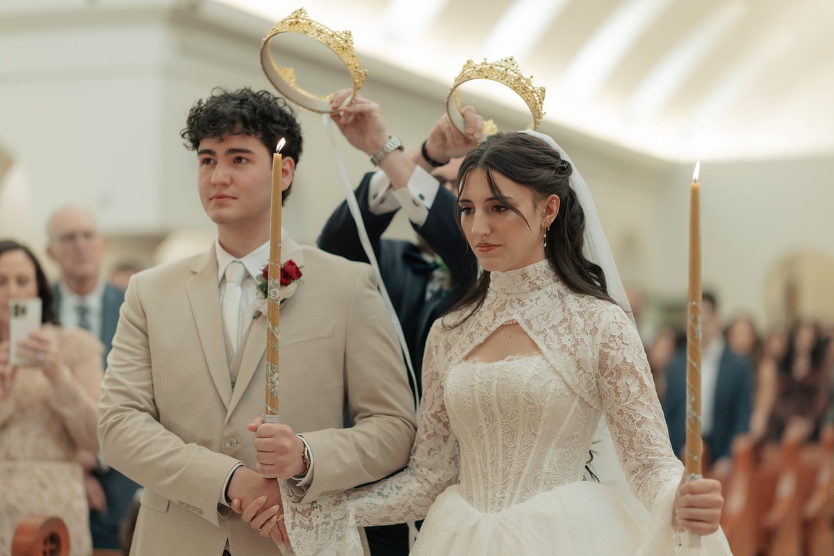 The crowned bride and groom hold candles during the wedding service
