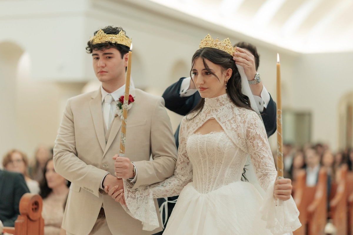 The crowned bride and groom hold candles during the wedding service
