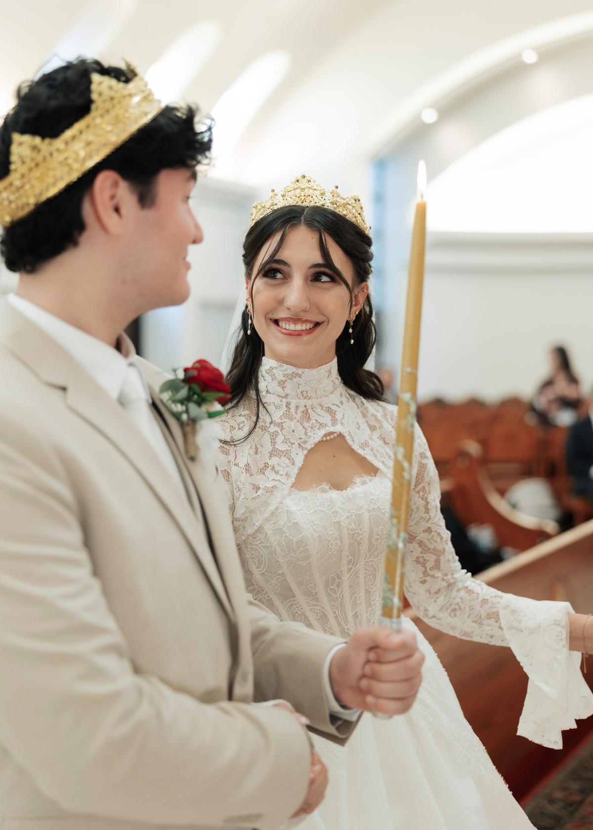 The crowned bride and groom hold candles during the wedding service
