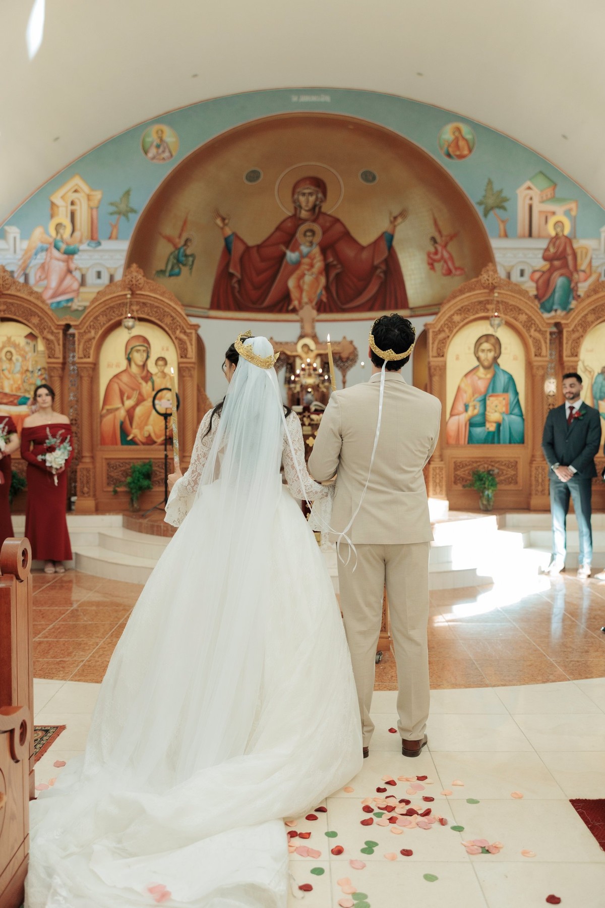 The bride and groom stand crowned beneath the painted apse
