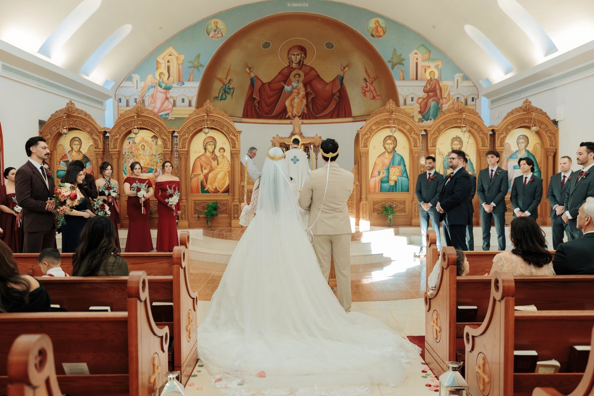 The bride and groom stand before the iconostasis during their wedding ceremony