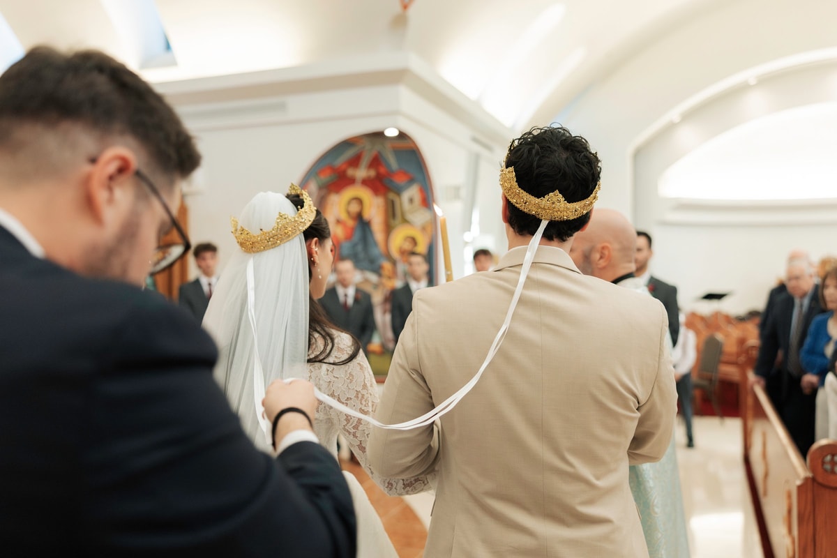 An Orthodox priest carries the Gospel while leading the crowned couple in procession