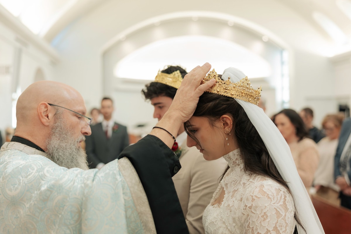 A priest adjusts the bride's wedding crown