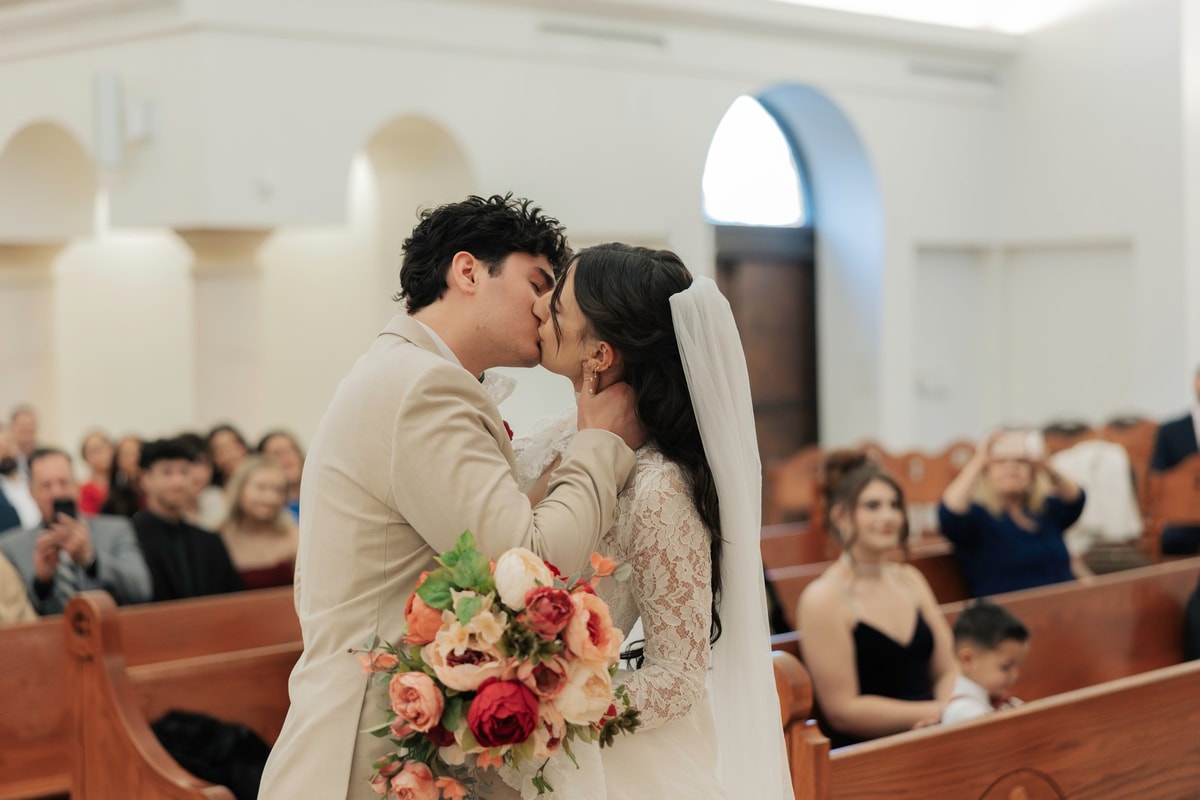 The bride and groom kiss inside an Orthodox church