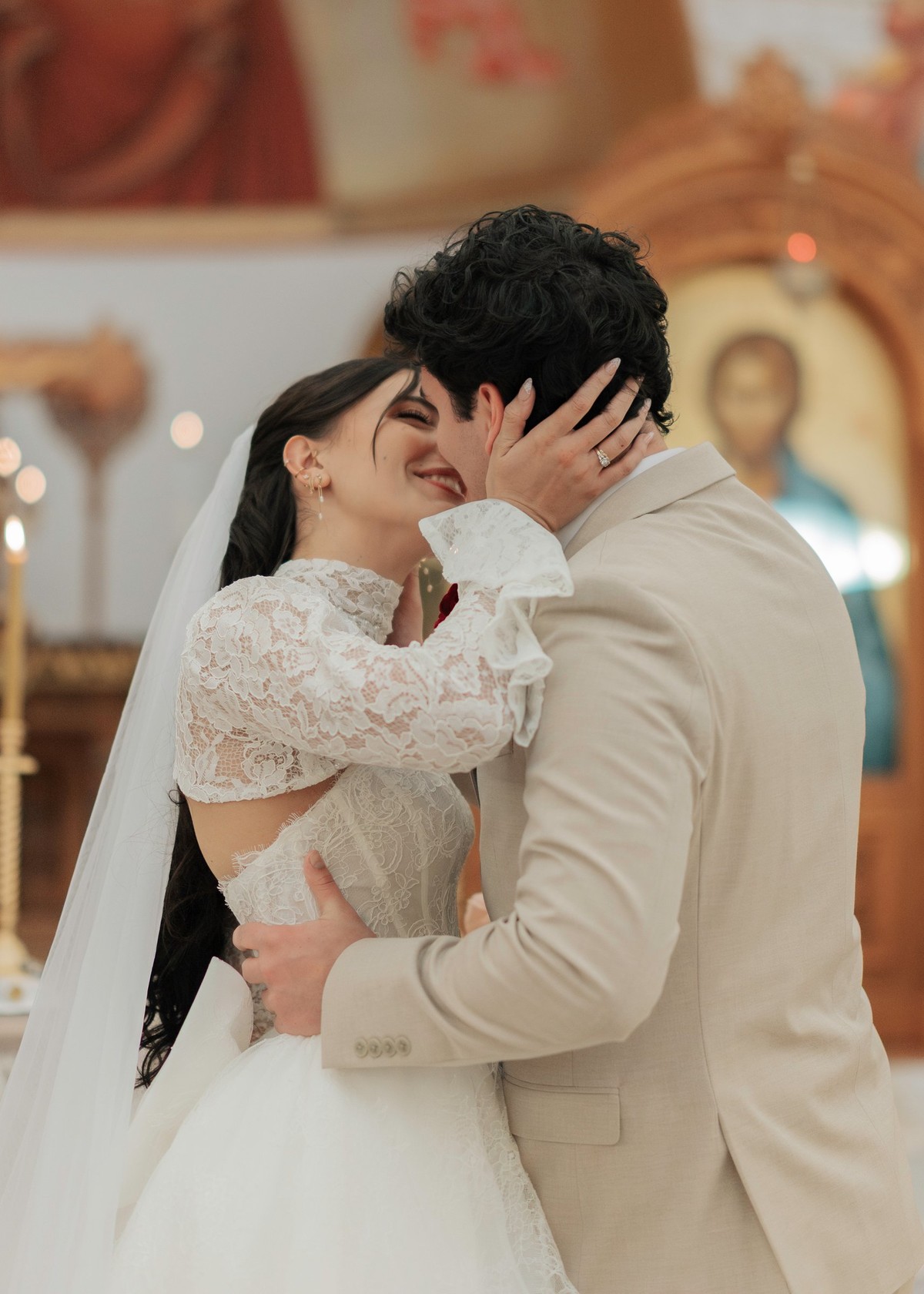 The bride and groom kiss inside an Orthodox church