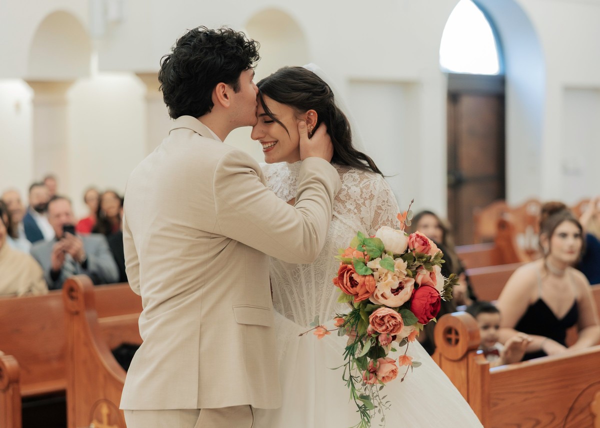The bride and groom kiss inside an Orthodox church
