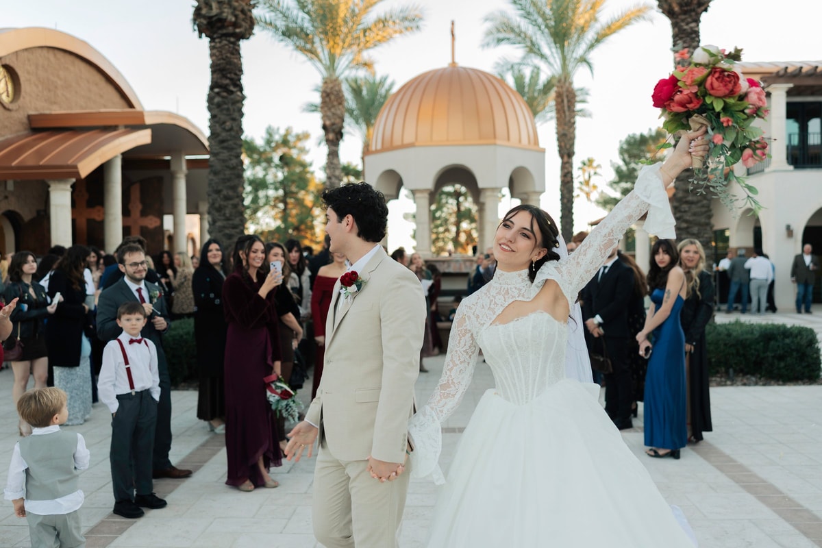 The bride lifts her bouquet while the groom looks on