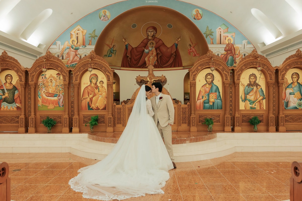 The bride and groom pose together before the iconostasis
