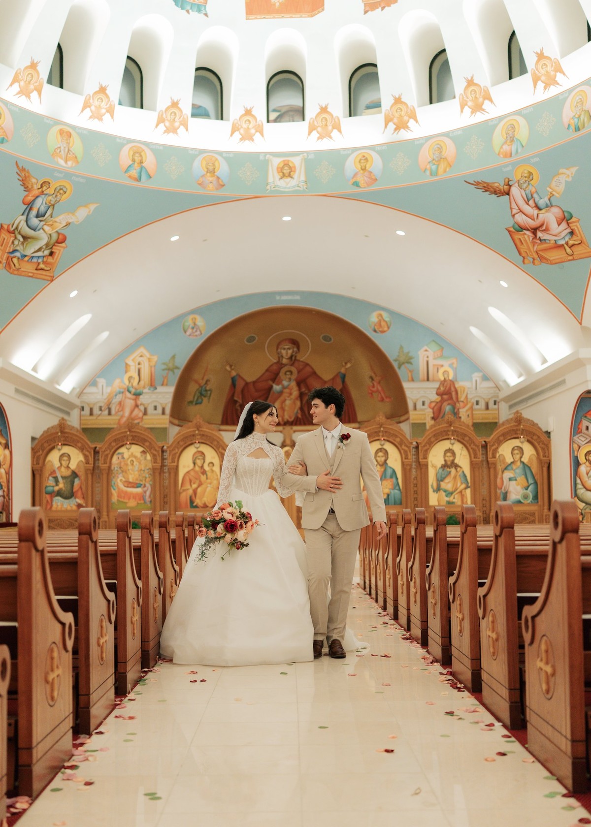 The newly married couple walks down the center aisle beneath the painted dome
