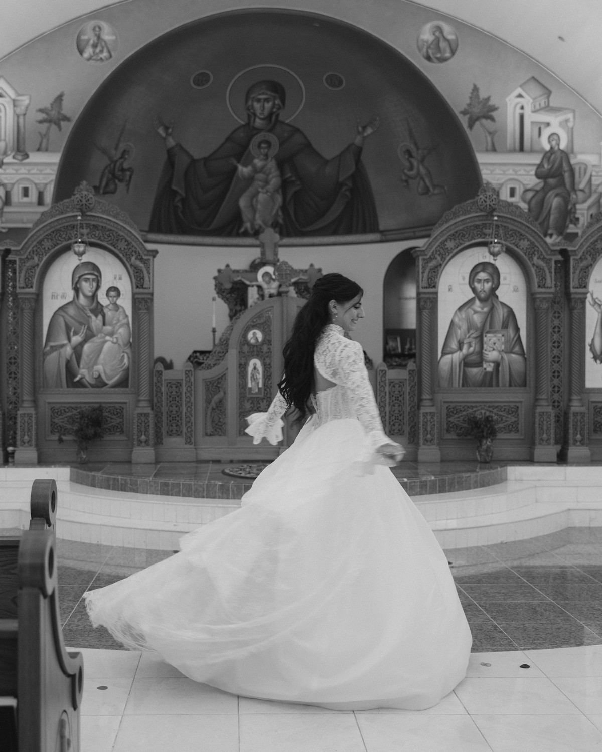 The bride turns in her wedding gown inside the nave in a black-and-white photograph