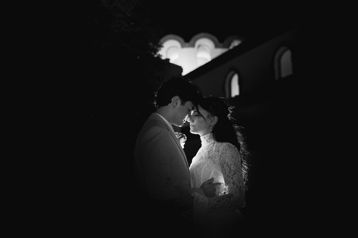 The bride and groom kiss outside the church at night