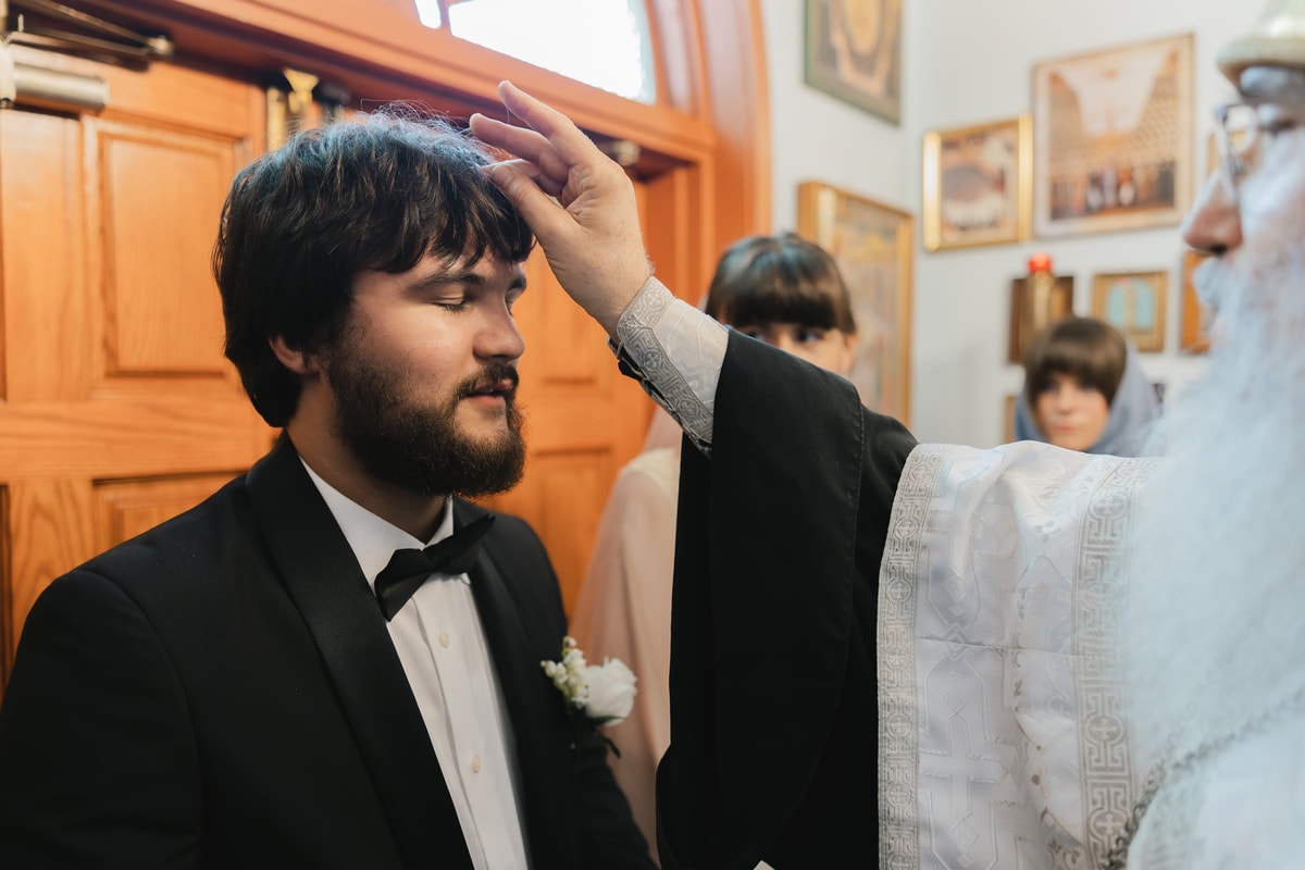 A bishop blesses the groom at the church entrance