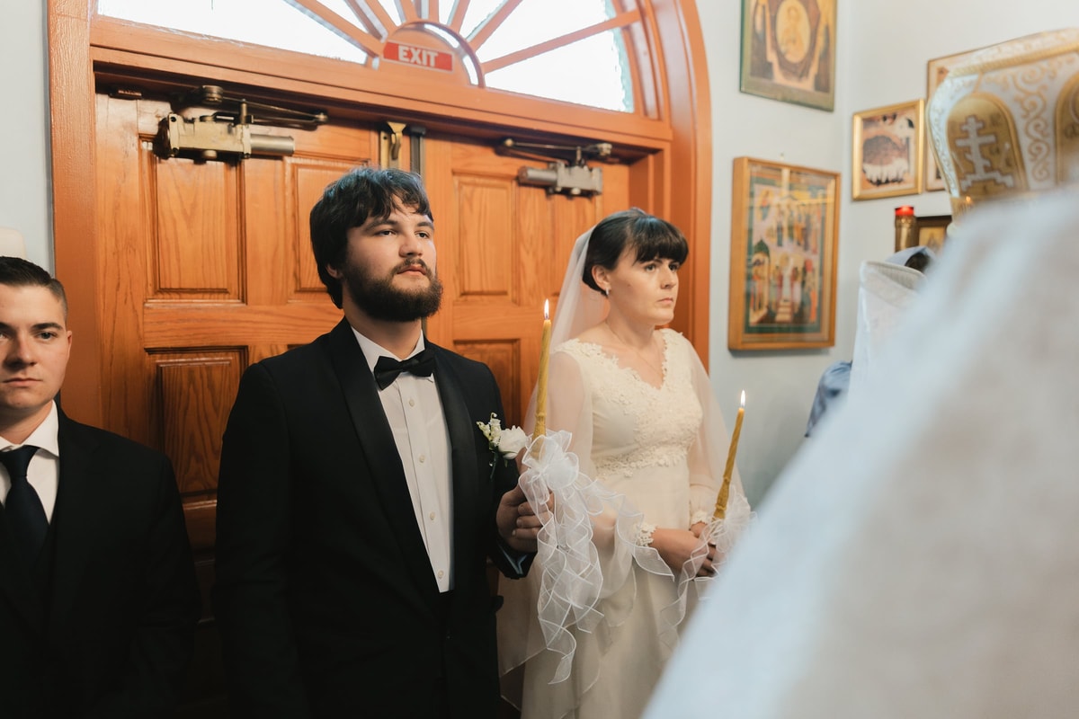 The bride and groom face the clergy at the church entrance