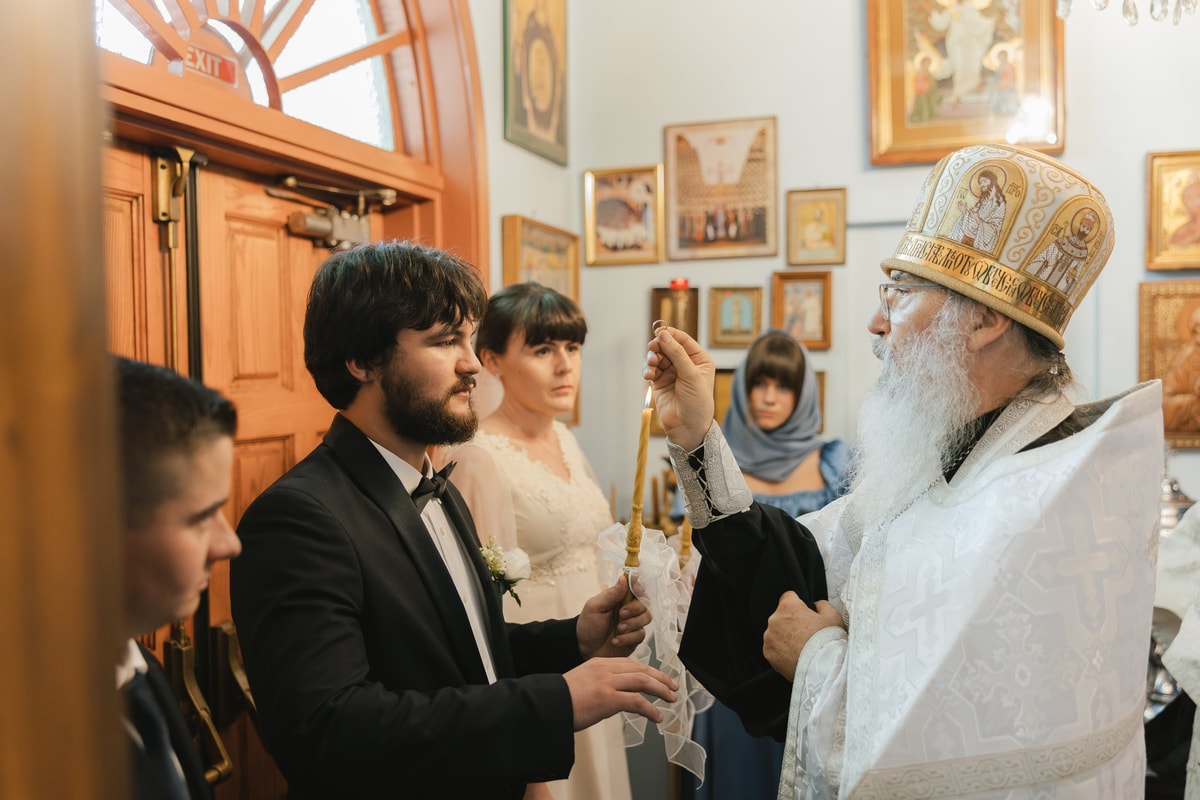 A bishop blesses the groom during the wedding service