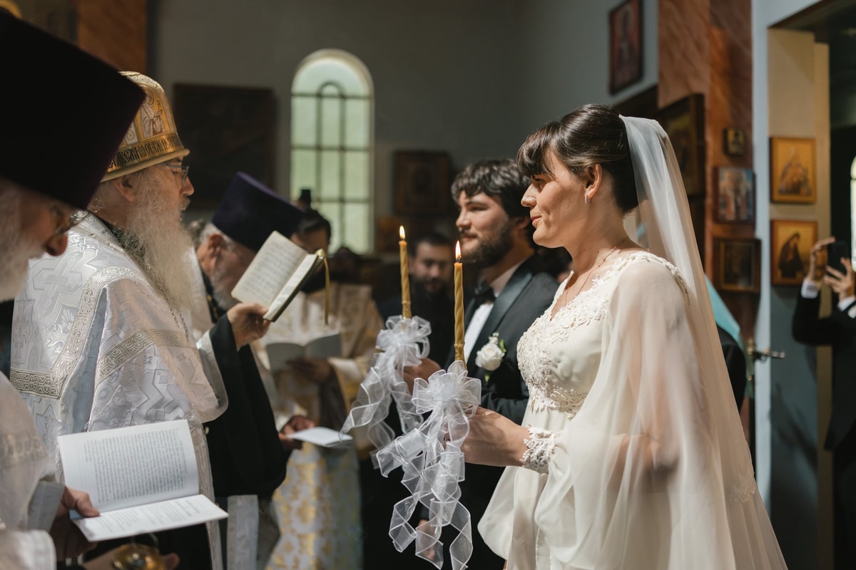 A bride listens to Orthodox clergy during the wedding service