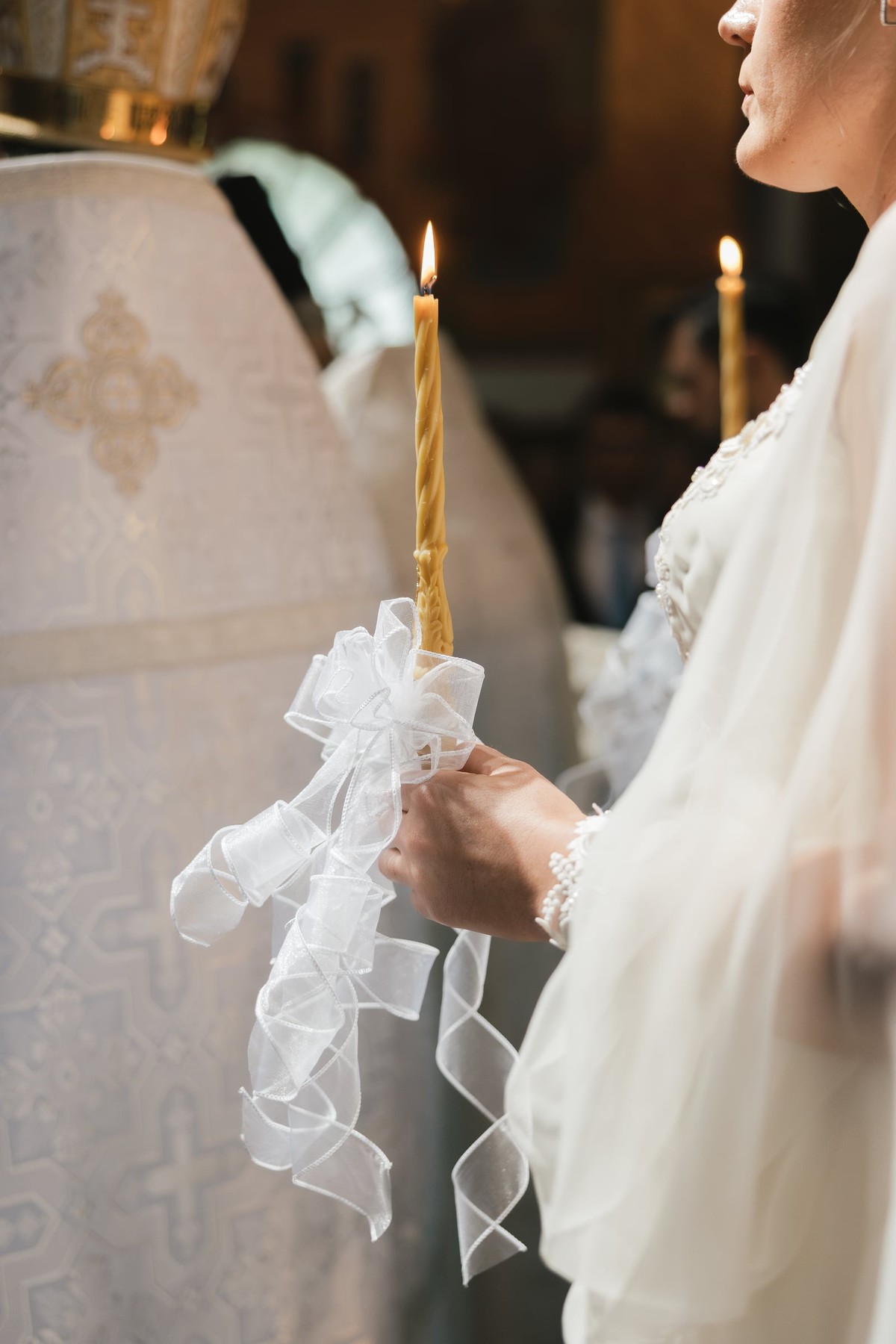 The bride holds a decorated wedding candle
