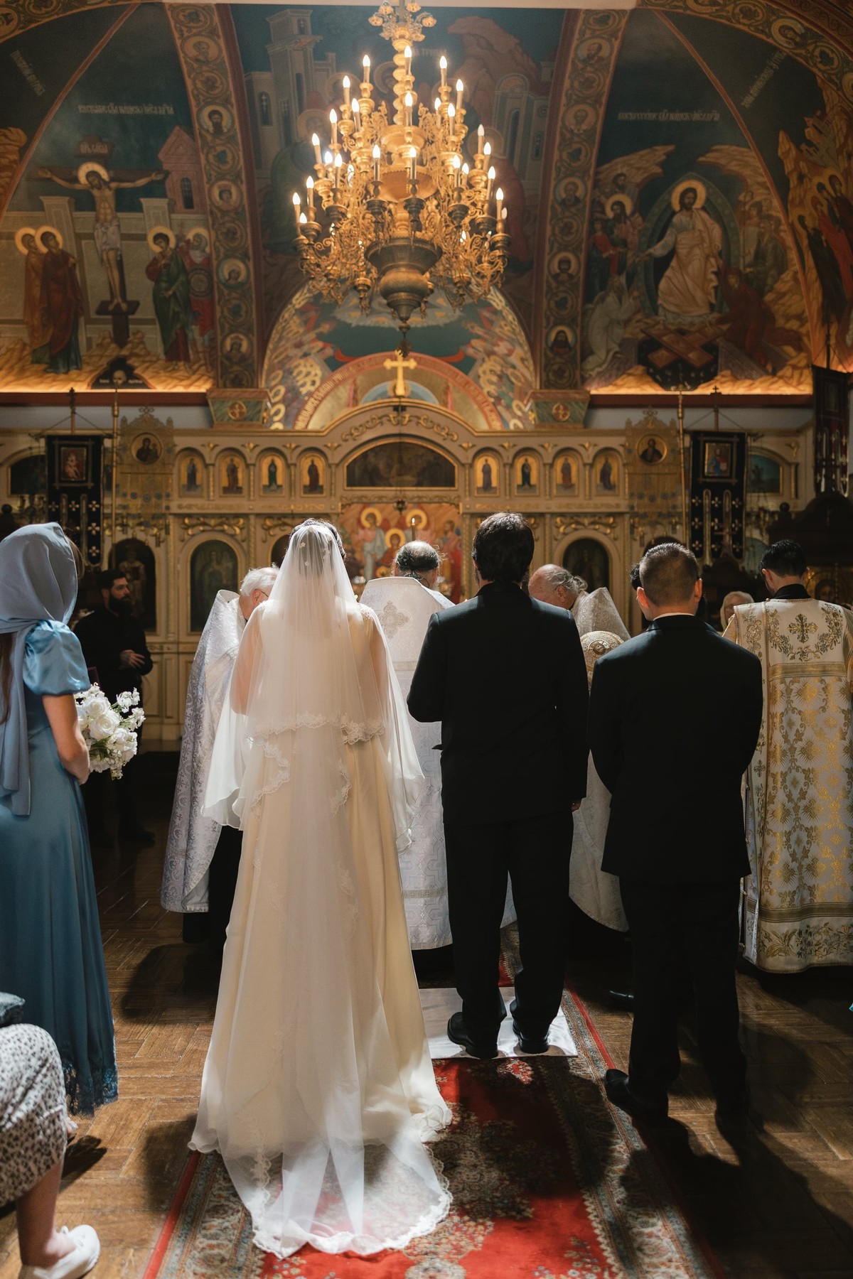 The bride and groom stand before a bishop and other Orthodox clergy during the wedding service