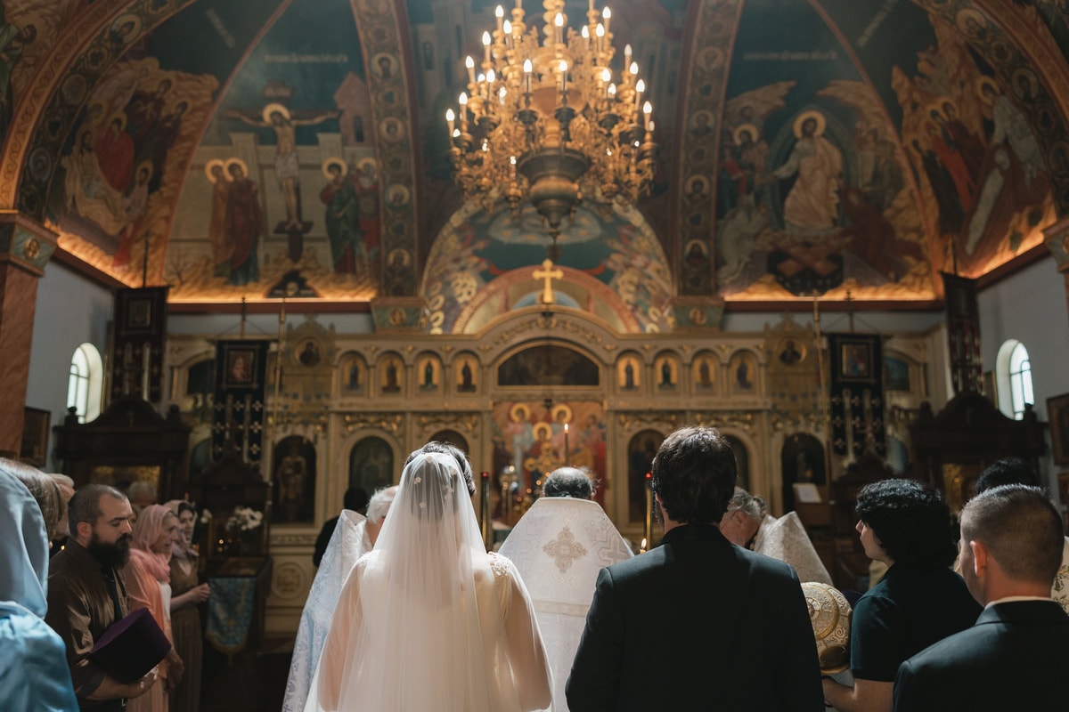 The bride and groom stand before a bishop and other Orthodox clergy during the wedding service