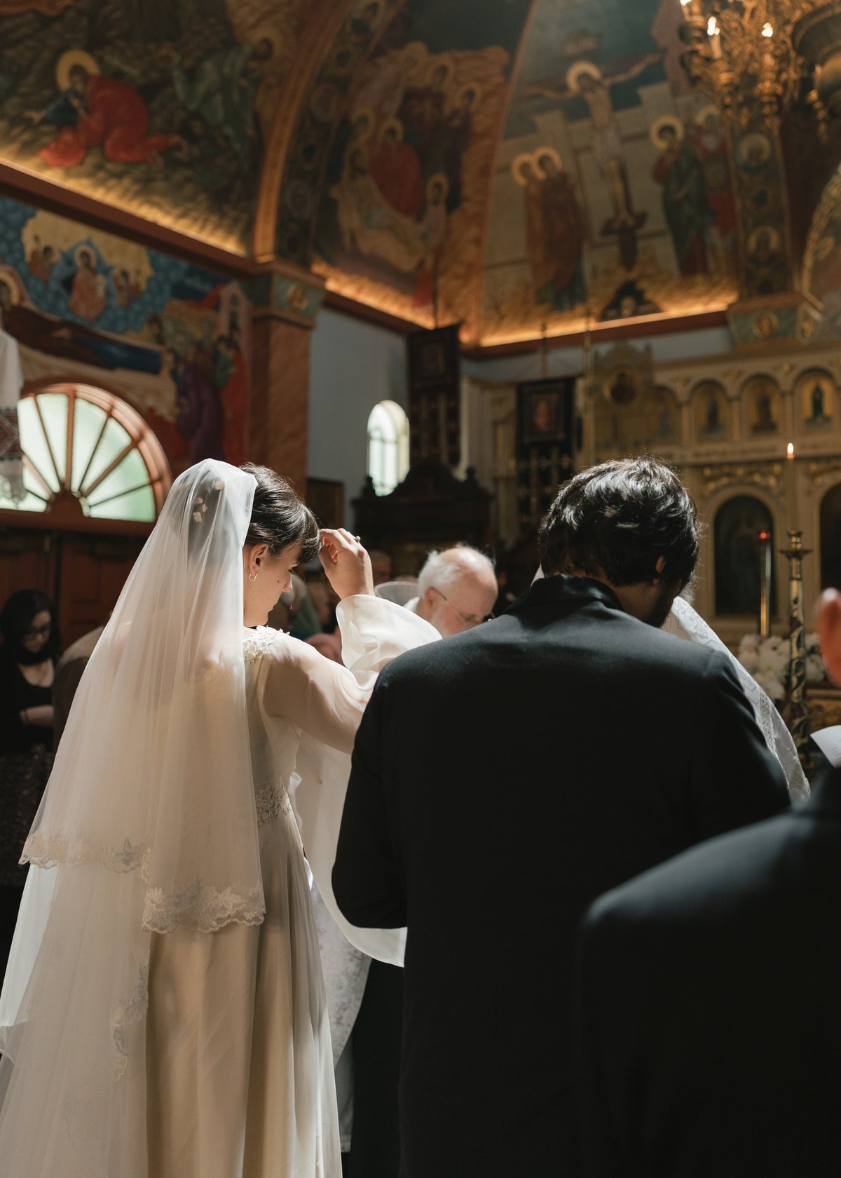 The bride and groom stand before a bishop and other Orthodox clergy during the wedding service