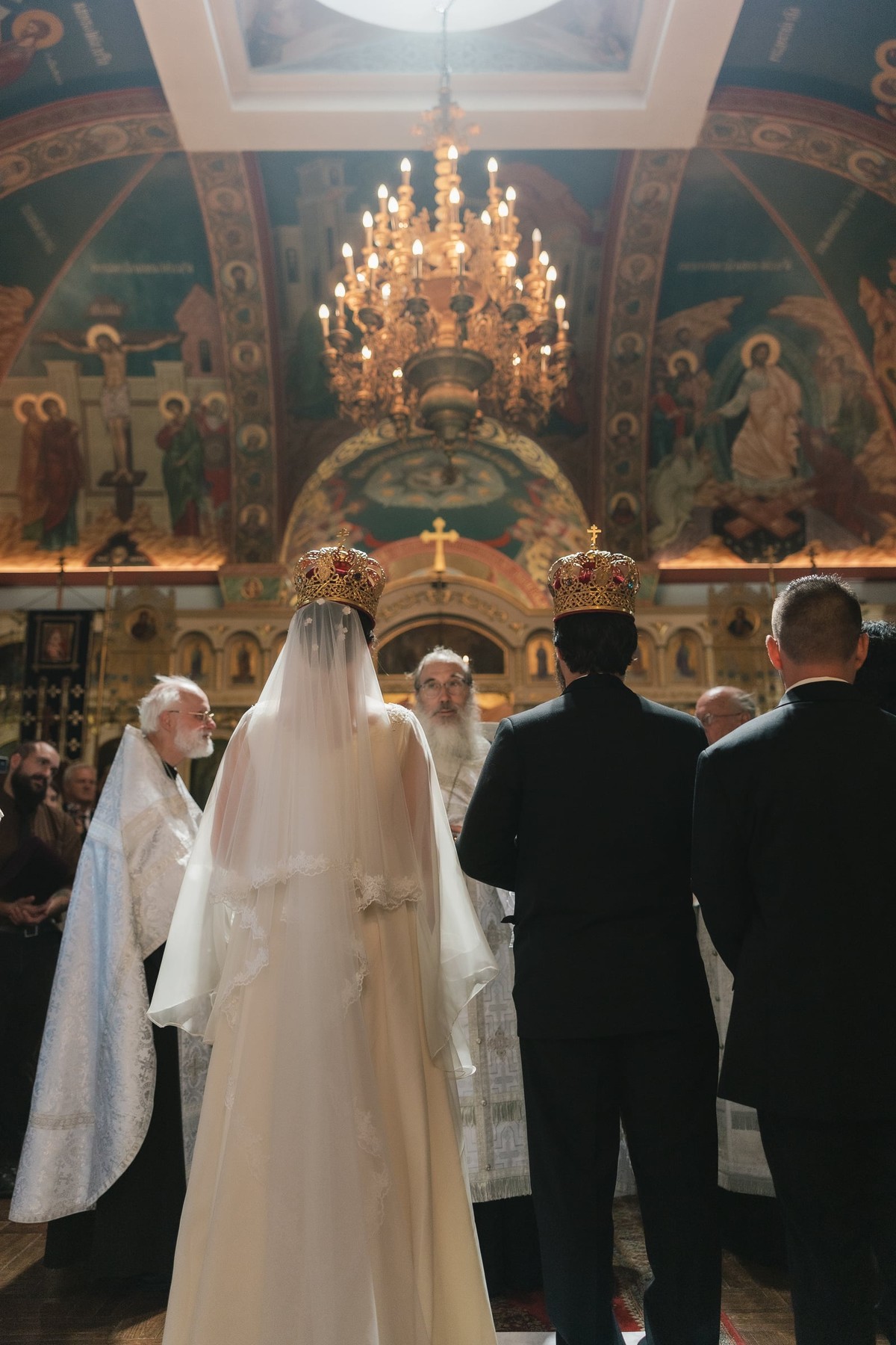 The bride and groom stand before a bishop and other Orthodox clergy during the wedding service