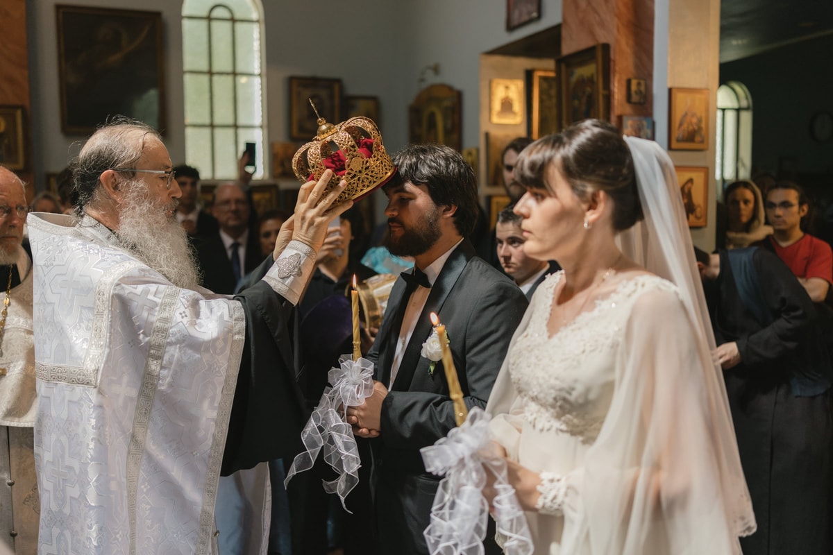 A priest raises a wedding crown above the groom
