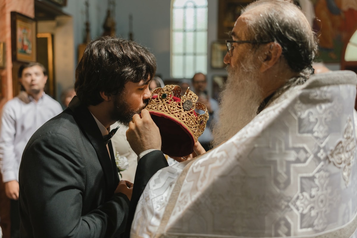 The groom kisses the wedding crown before it is placed on him